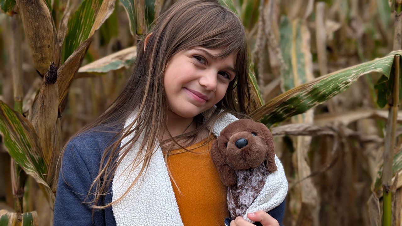 Éowyn Breeze holding a stuffed dog in a cornfield
